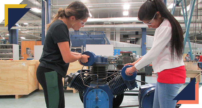 Two students taking apart a large engine