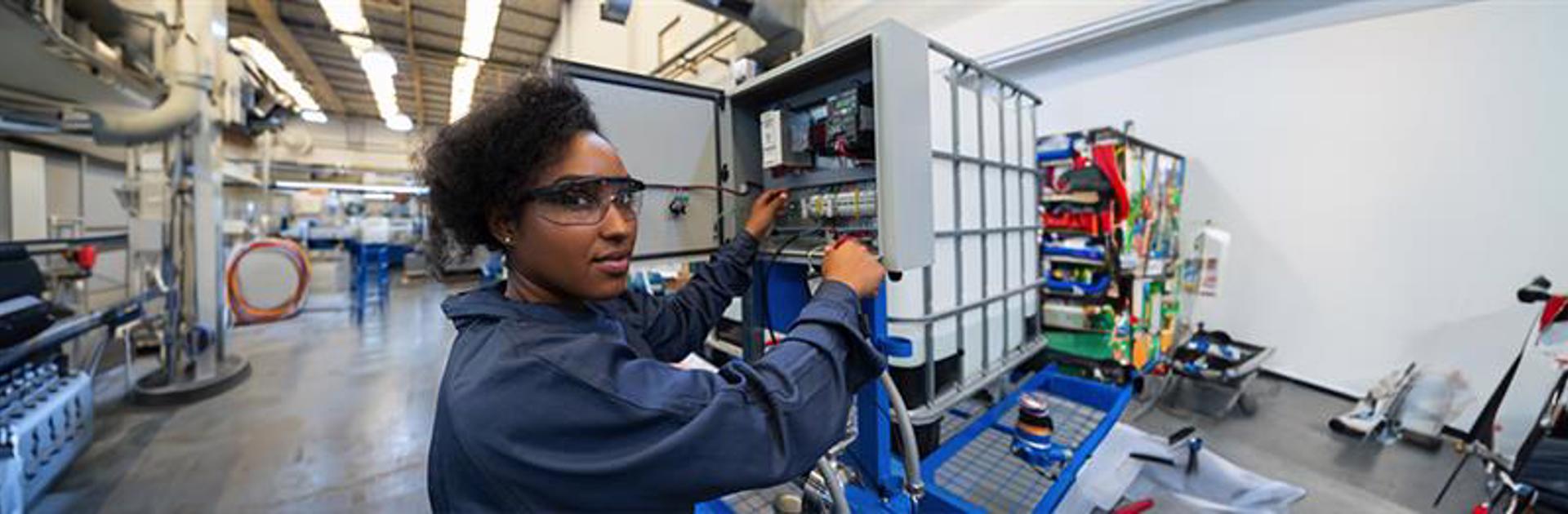 Female trades student practicing on electric switchboard