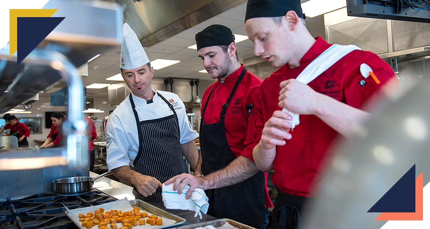 Trades instructor inspecting two culinary students' meal